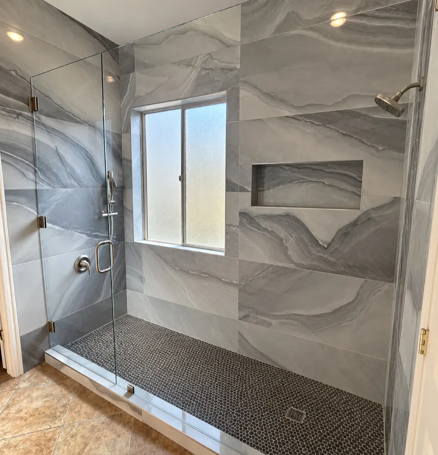 Large tile walk in shower with niche and glass panel