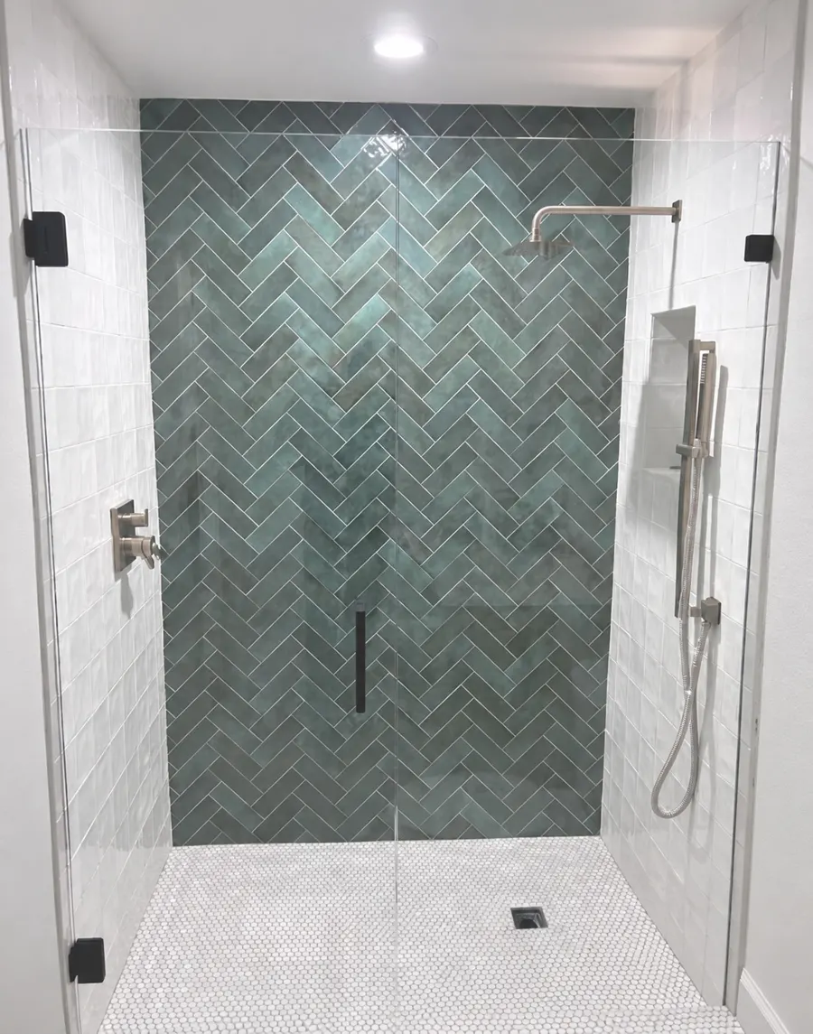 Walk in shower with green herringbone tile